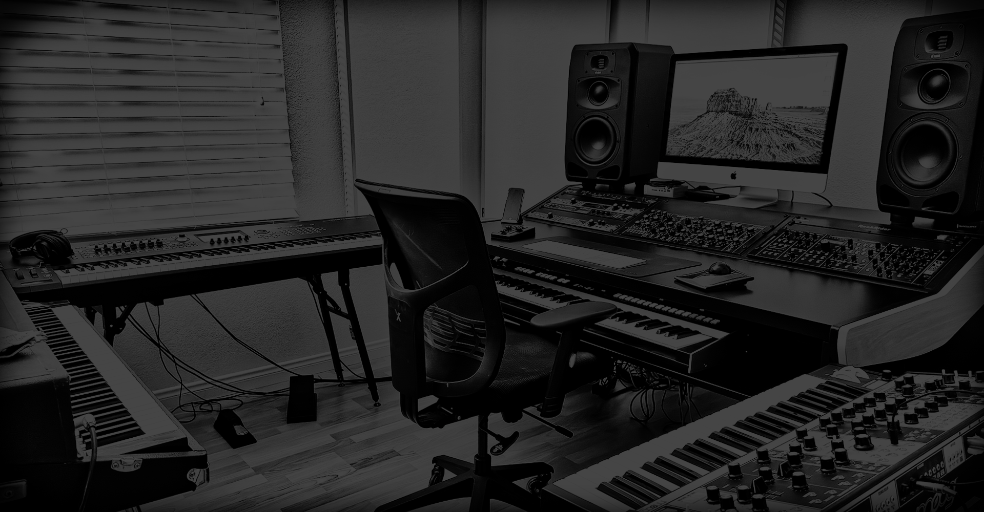 Linwood Bell’s professional music production studio featuring keyboards, synthesizers, mixing console, and a large monitor.